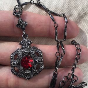 Dark metal necklace with red gemstone pendant